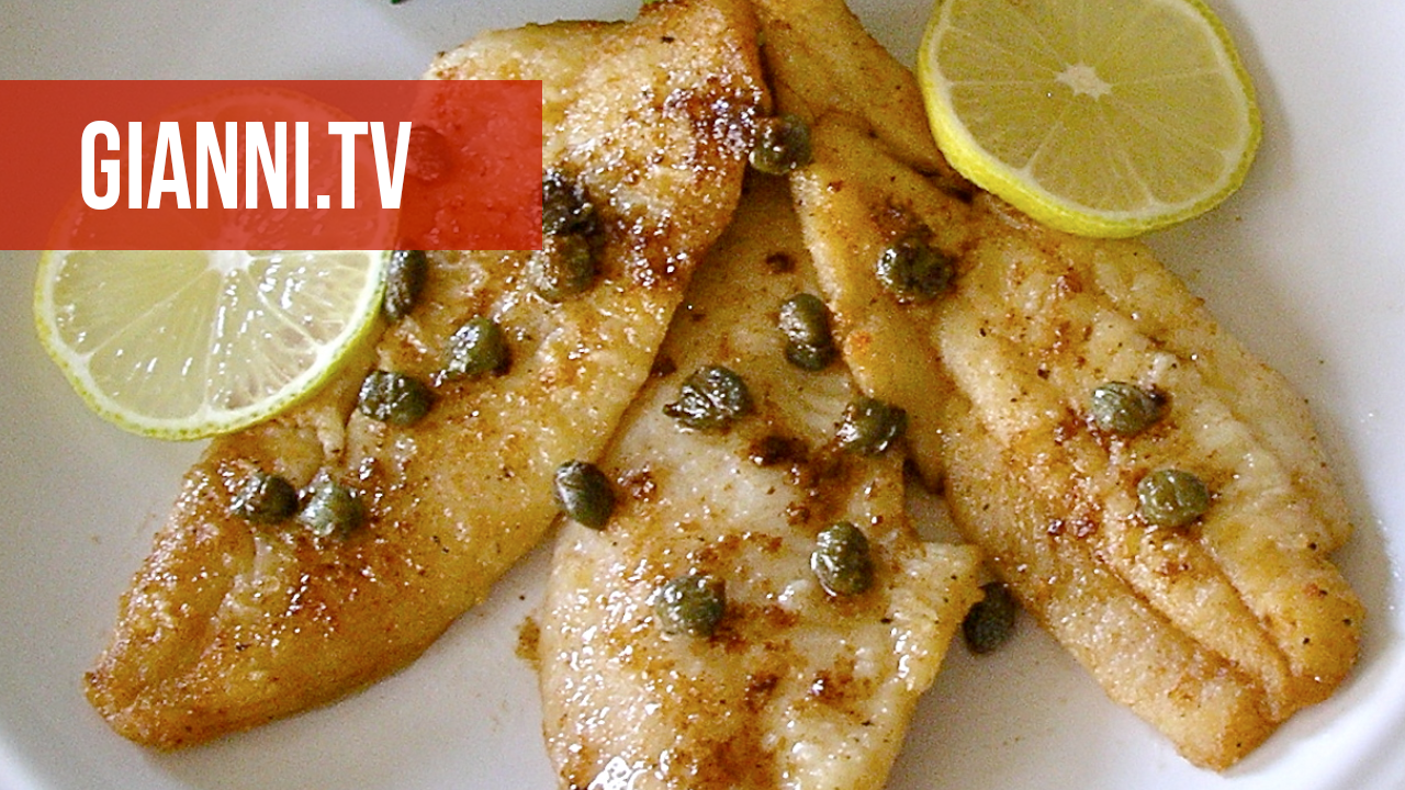 Plate with sole fillets, caper sauce and lemon slices.